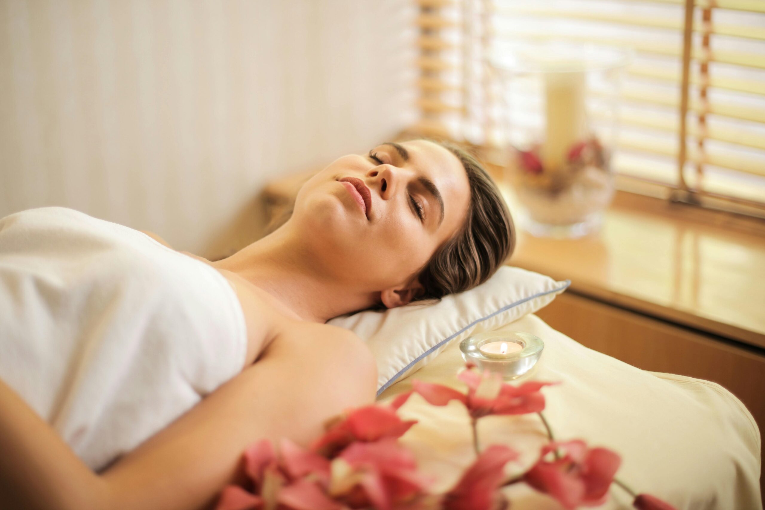 mujer tomando un descanso en una cama de spa con flores a un lado